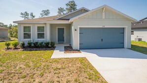A single-story house with a garage, a front door, and a small porch area. - Escape the Winter! Cozy 3BR Retreat in Sunny Ocala, Florida (Ocala)