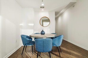A conference room with a round table, four blue chairs, a round mirror, and a vase on the table. - The Navagio' Waterfront Penthouse 3 Levels, Private Rooftop Boats View Parking (Marina del Rey)