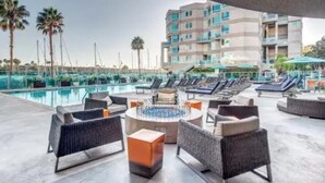 A poolside area with lounge chairs, a fire pit, and a view of a building with balconies. - The Navagio' Waterfront Penthouse 3 Levels, Private Rooftop Boats View Parking (Marina del Rey)