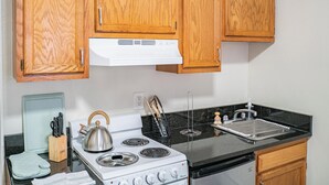 Una cocina con armarios de madera, estufa, fregadero y hervidor.