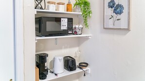 Una cocina equipada con microondas, tostadora, cafetera y un cuadro con motivos florales en la pared.