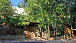 Una piscina rodeada de vegetación tropical y una estatua de jirafa.