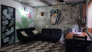 Una habitación con pared de piedra, un mural de leopardo, un sofá negro y piso estampado.