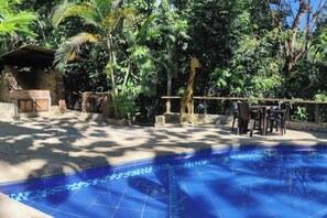 A pool area with a tiled floor, surrounded by lush greenery and a stone structure. - Casa Verde Nature Reserve (dos quebradas)