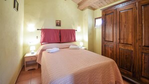 A bedroom with a bed, two bedside tables with lamps, a wooden wardrobe, and a red curtain. - 4 bedroom cozy home in Montenero Val Cocchiar (Montenero Val Cocchiar)