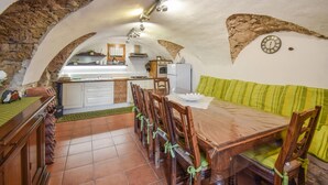 A dining area with a wooden table and chairs, a green sofa, and a kitchen in the background. - 4 bedroom cozy home in Montenero Val Cocchiar (Montenero Val Cocchiar)
