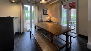 A dining area with a long wooden table, benches, and a ceiling light fixture. - MENDIA - SAINT PIERRE D'IRUBE (SAINT-PIERRE-D'IRUBE)
