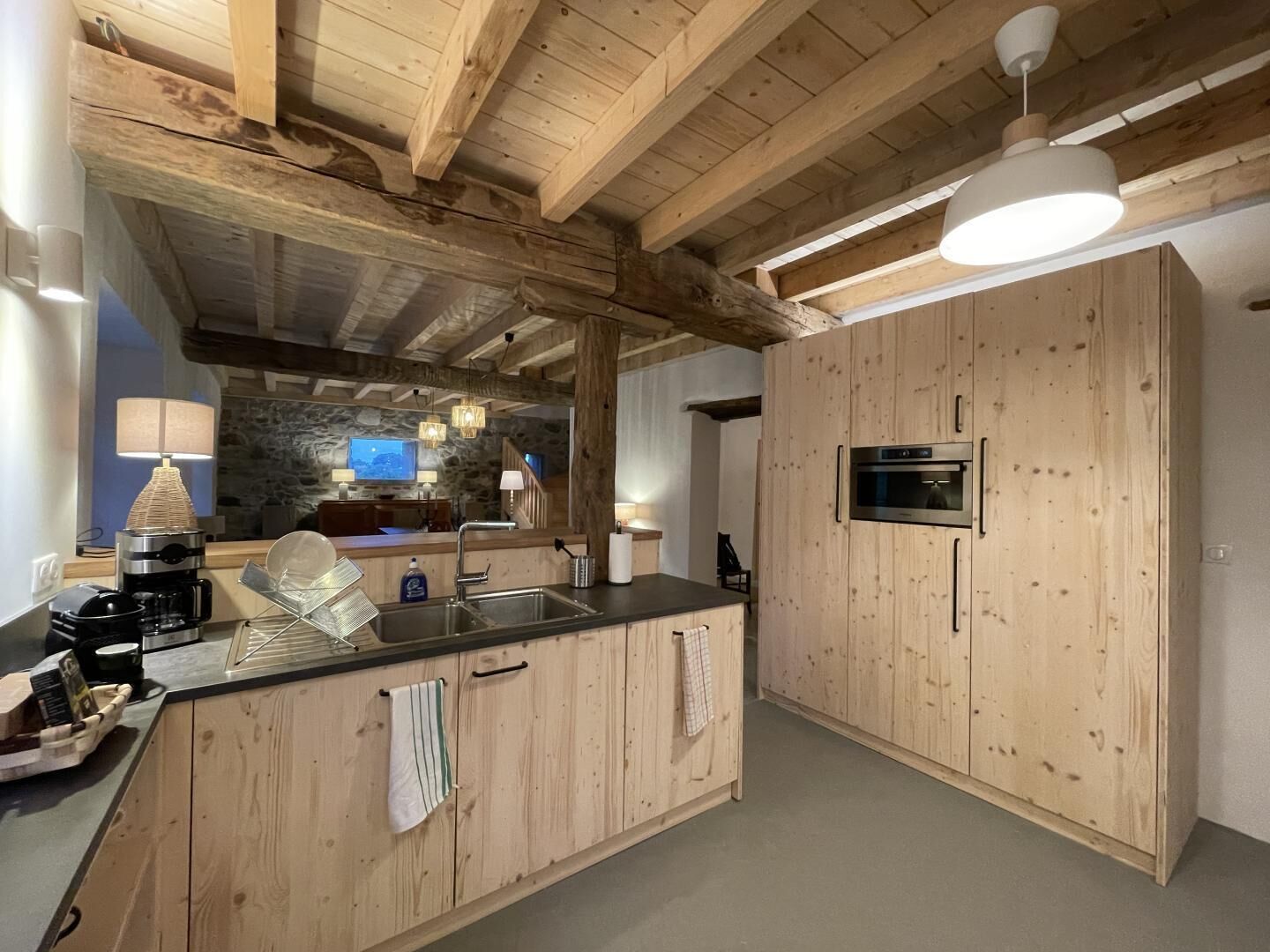 A kitchen with wooden cabinets, a built-in oven, and a stone wall in the background.
