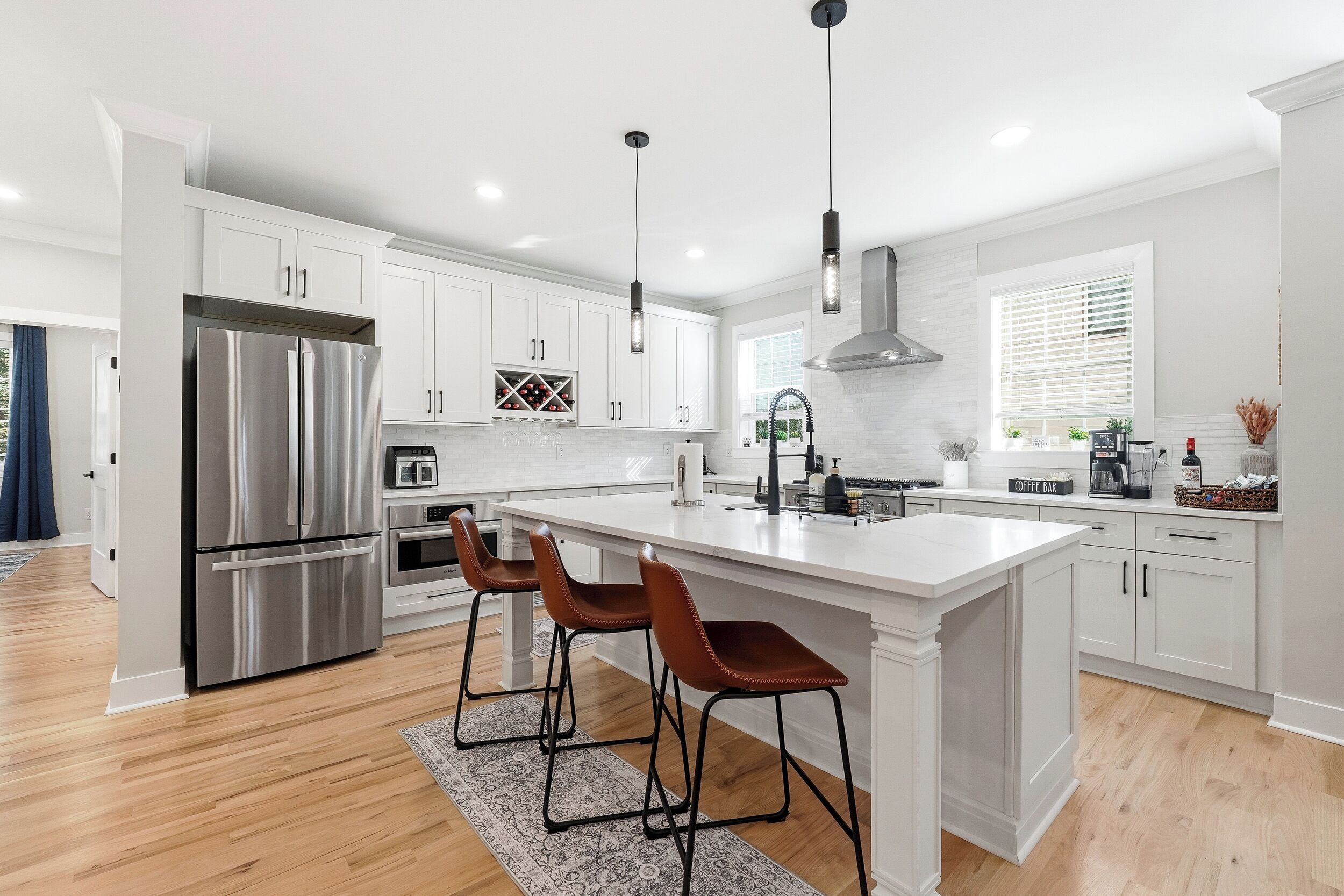 A modern kitchen with white cabinets, stainless steel appliances, and a central island with bar stools.
