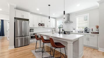 A modern kitchen with white cabinets, stainless steel appliances, and a central island with bar stools.
