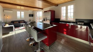 Een moderne keuken met een centraal eiland, houten plafond en grote ramen.