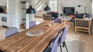 A modern kitchen with white appliances, a dining area with a wooden table and purple chairs, a black leather sofa, and a TV in the background. - Amazing home in Farsø with house a panoramic view (Farsø)