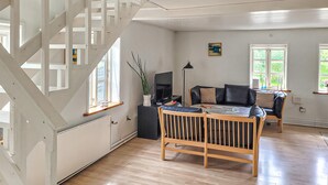 A modern living room with a wooden staircase, a sofa, a TV, and a dining area. - Amazing home in Farsø with house a panoramic view (Farsø)