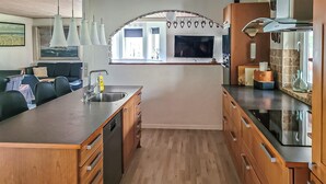 Eine moderne Küche mit Holzausstattung, einem Edelstahlspülbecken und einer großen Kochinsel.