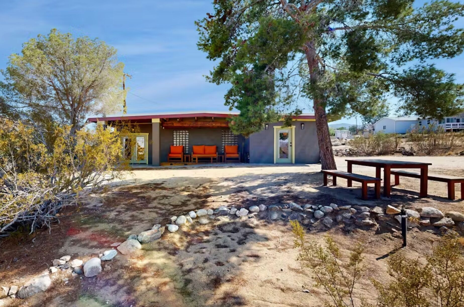 Desert exterior featuring a shaded patio with orange seating and a nearby picnic table.