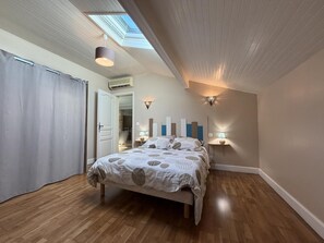 Ein Schlafzimmer mit einem Bett, Holzboden, einem Oberlicht und einer Tür.