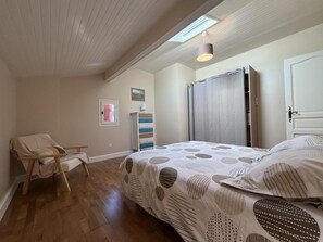A bedroom with a sloped ceiling, a bed with a patterned bedspread, a wooden chair, a dresser, and a wardrobe. - BIXTA EDER - MACAYE - B&B (MACAYE)