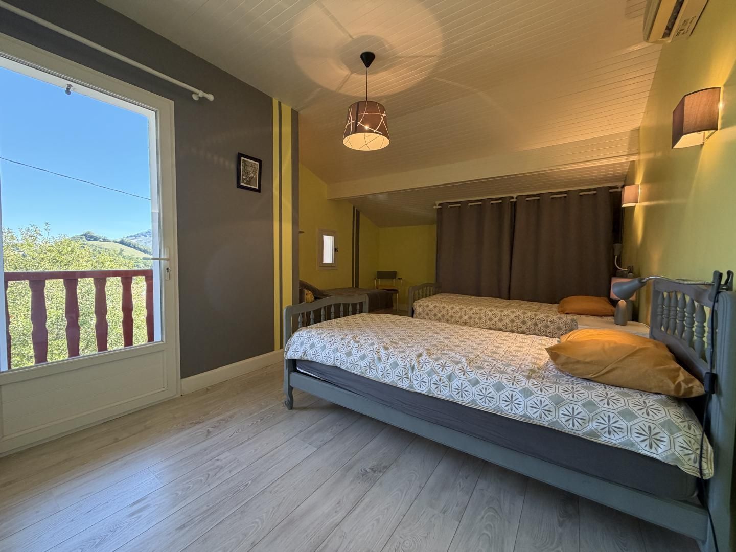 A bedroom with a bed, a bedside table, a lamp, and a view of the outdoors.