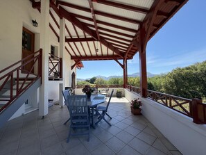 A covered patio with a table and chairs, a staircase, and a view of the mountains. - BIXTA EDER - MACAYE - B&B (MACAYE)