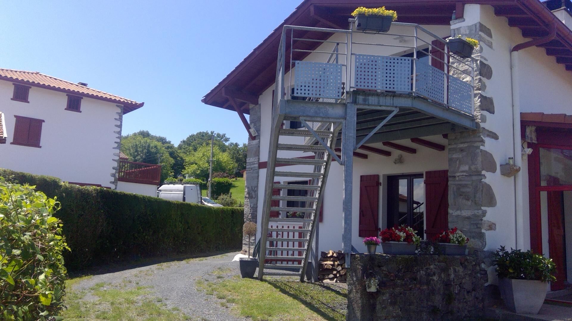 Een huis met twee verdiepingen en een houten trap die naar een balkon leidt.