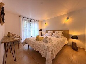 A bedroom with a bed, two bedside lamps, a table with a chair, and a window with curtains. - TEILARIA - SARE - Gîte (SARE)