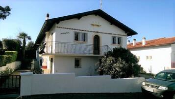 Une maison à deux étages avec un balcon et une voiture garée devant.