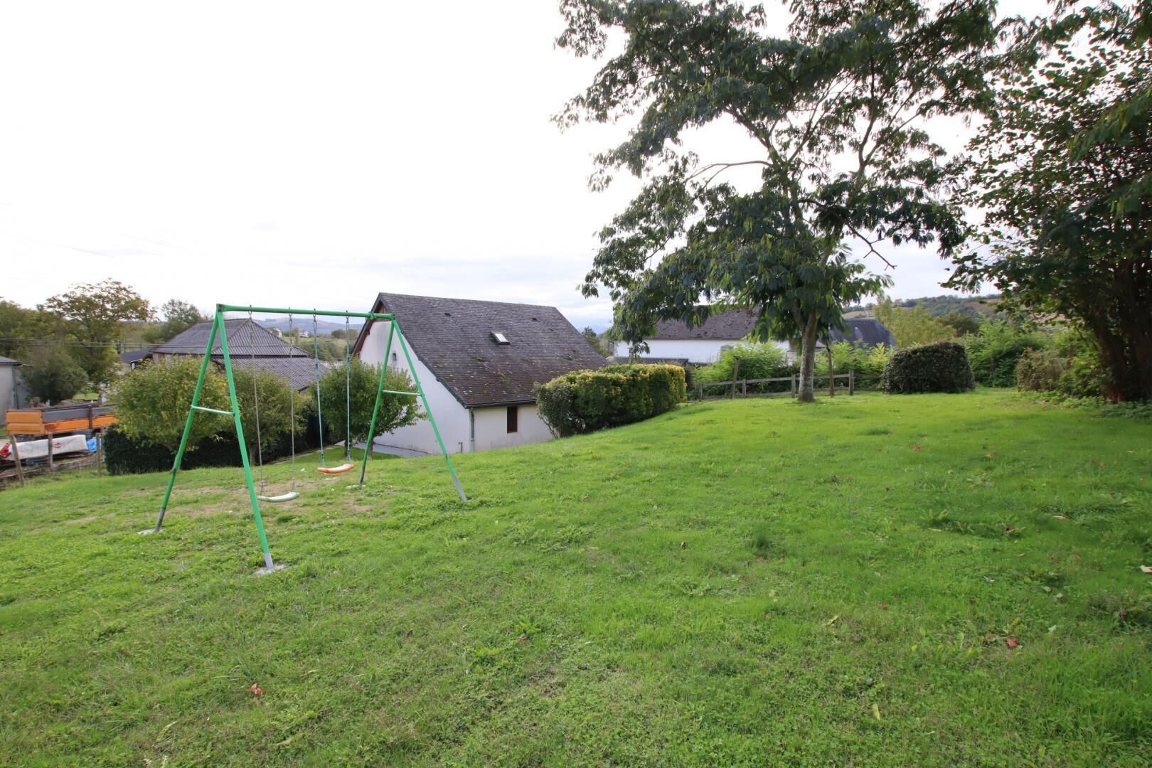 A grassy backyard with a swing set and a house in the background.