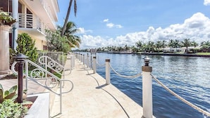 Hotel aan het water met een verharde promenade, palmbomen en uitzicht op het water.