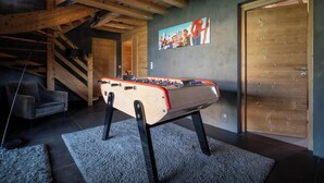 A cozy room with a foosball table, a gray sofa, and a staircase.