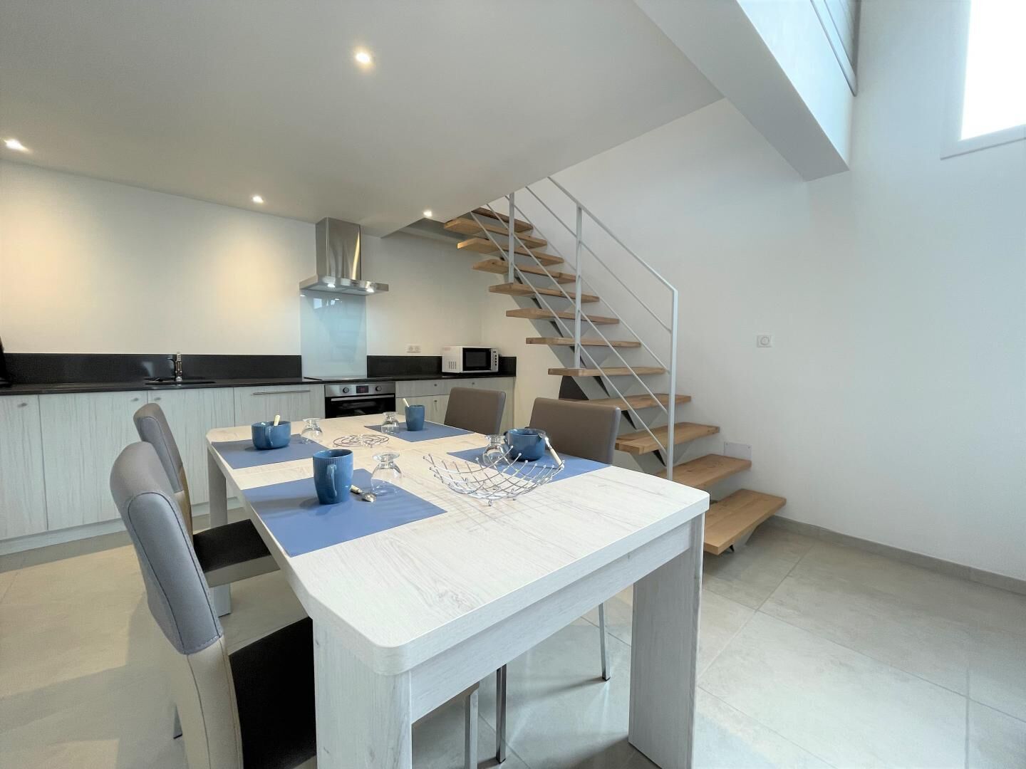 Une cuisine moderne avec un coin repas, un escalier et une vue sur l’étage supérieur.