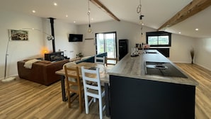 A modern kitchen with a central island, wooden flooring, and exposed beams. - MENDIBURIA - IHOLDY - Gîte (IHOLDY)
