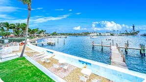 A waterfront view with a dock, palm trees, and a lighthouse in the distance. - Condo With Heated Pool! Beach & Ocean Access! (Pompano Beach)