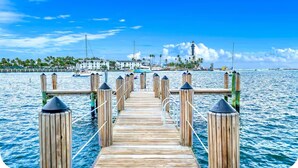 A wooden pier leading to a waterfront area with boats and a lighthouse in the background. - Condo With Heated Pool! Beach & Ocean Access! (Pompano Beach)