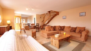 Ein gemütliches Wohnzimmer mit einer Couch, einem Sessel, einem Holztisch und einer Treppe.