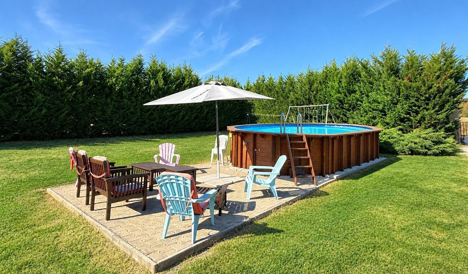 A backyard with a hot tub, a pool, and outdoor furniture.