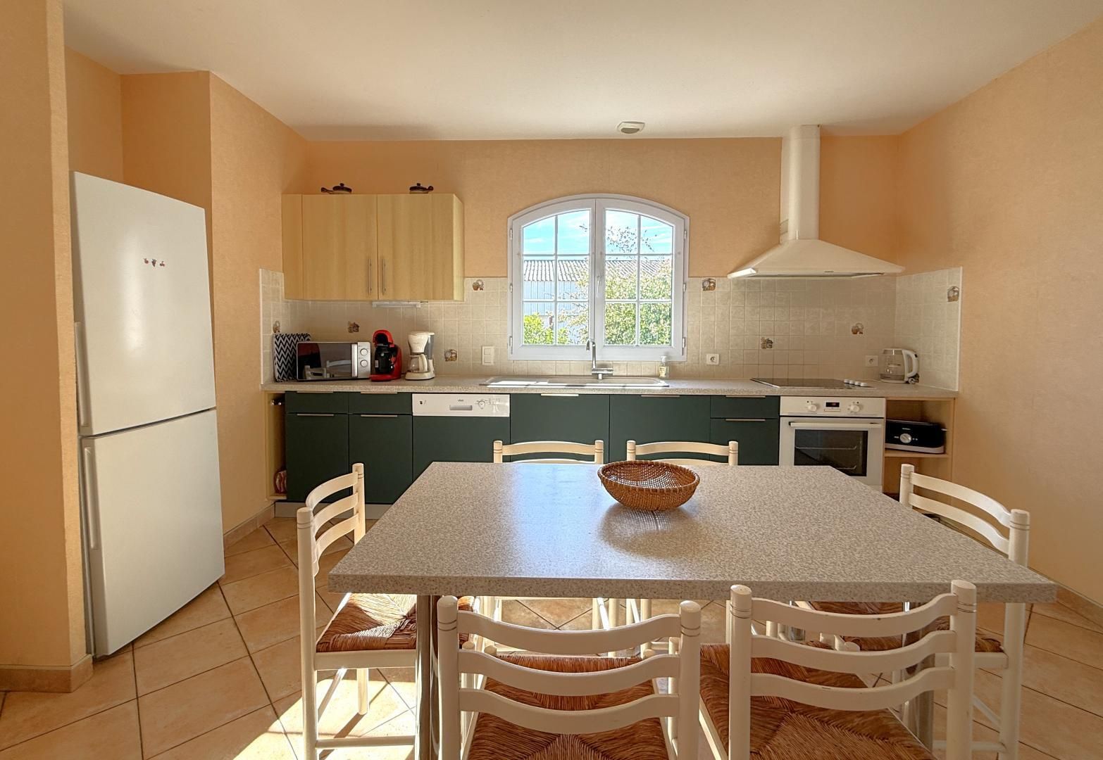 A compact kitchen with a dining area, equipped with a refrigerator, stove, and a window providing natural light.