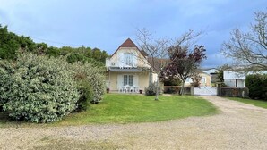 Ein zweistöckiges Haus mit Balkon, Rasen und Kiesweg.