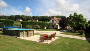 Ein Wohnhaus mit Schwimmbad, Außenbereich zum Sitzen und einem gepflegten Rasen.