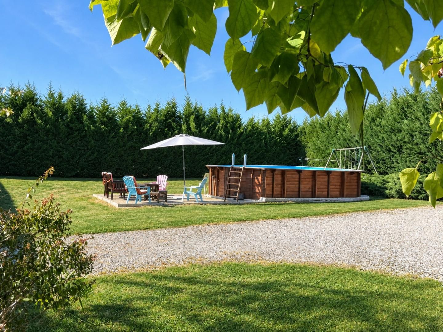 A backyard with a wooden deck, outdoor furniture, and a covered seating area.