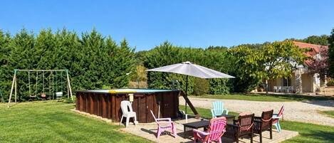 A backyard with a wooden playhouse, outdoor seating, and a swing set.