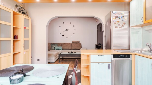 A compact kitchen with a refrigerator, dishwasher, and a dining area with a table and chairs.
