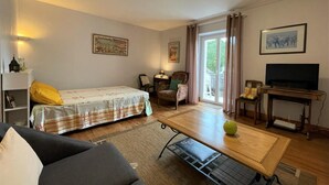 Een gezellige woonkamer met een bed, een bank, een tafel en een televisie.