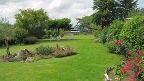 Een verzorgde tuin met gazon, een zitplek en diverse planten.