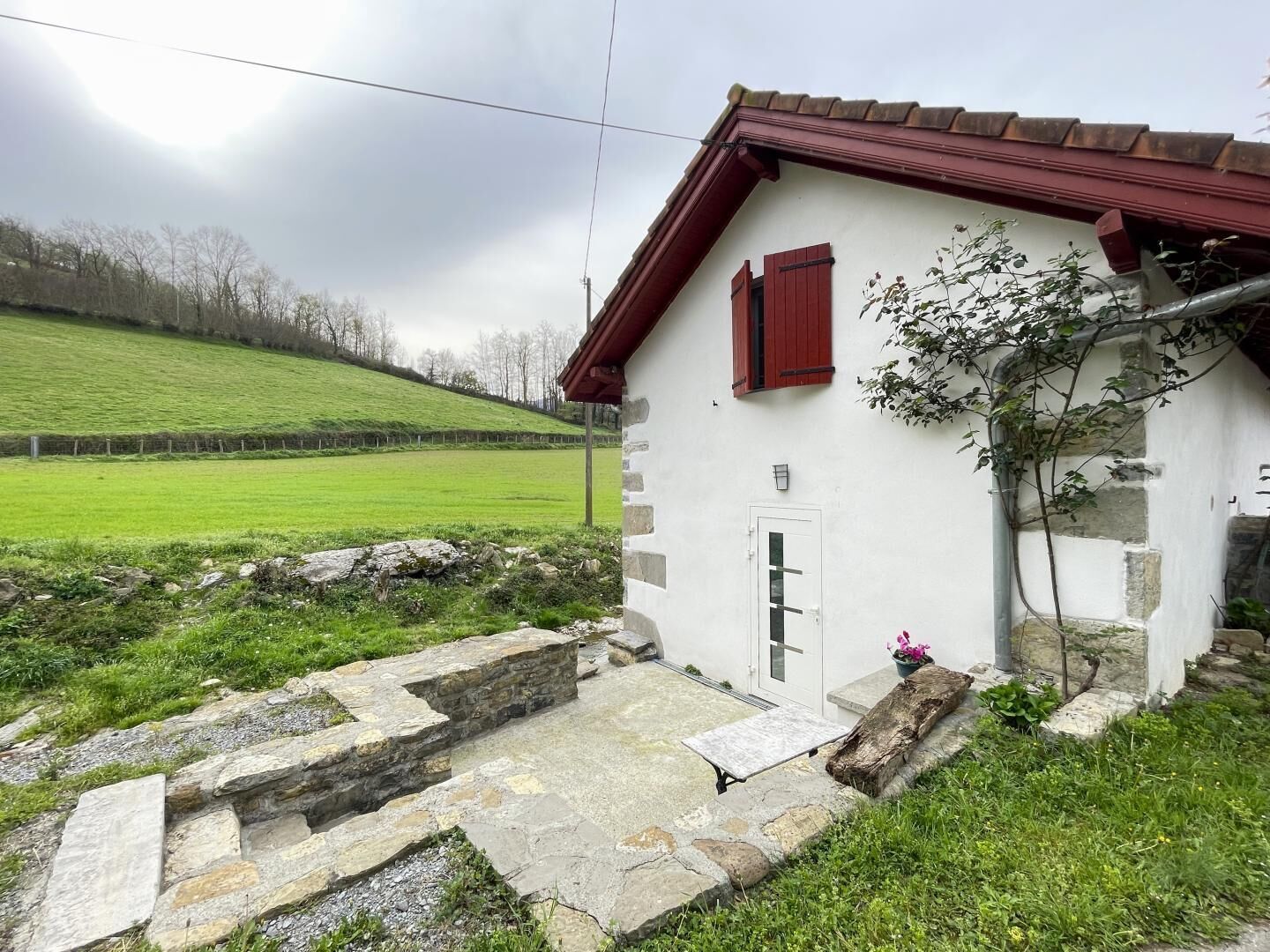 Ein rustikales Steinhaus mit rotem Dach und einer kleinen Veranda.