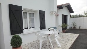 A white building with a tiled patio, a round table, and white chairs. - IRIBURU-BERRIA - SARE (SARE)