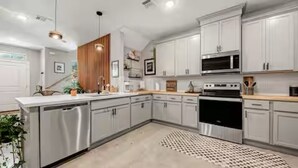 A modern kitchen with stainless steel appliances, white cabinetry, and a patterned rug. - The Hard Rock Condo! (Bryan)