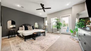 A bedroom with a bed, bedside tables, a ceiling fan, a large window, and a view of the outdoors. - The Hard Rock Condo! (Bryan)