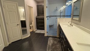 A modern bathroom with a walk-in shower, a separate toilet, and a vanity with a large mirror. - Soothing 4-bedroom house with AC in charming Plano (Plano)