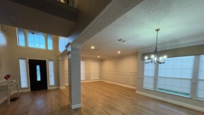 A spacious room with hardwood flooring, large windows, and a chandelier. - Soothing 4-bedroom house with AC in charming Plano (Plano)