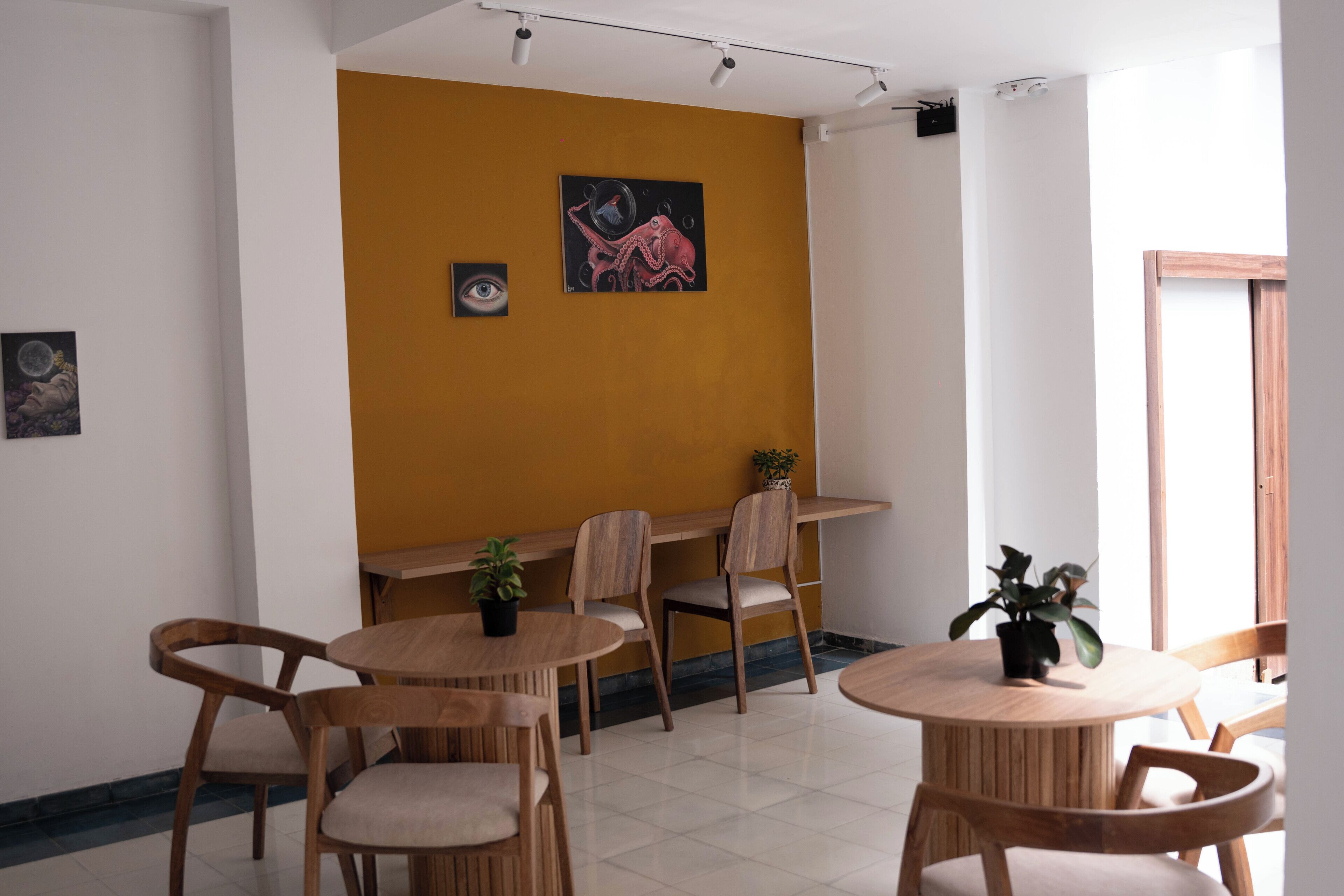 Una habitación con un muro amarillo de acento, muebles de madera y obras de arte.